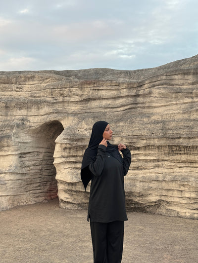 femme voilée qui porte un ensemble de sport modeste noir, sportwear et activewear, hijab de sport noir top oversize et pantalon modeste